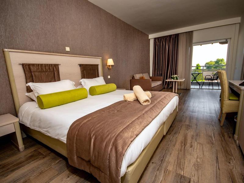 Cozy hotel room with large bed, soft lighting, wooden flooring, and a balcony view.