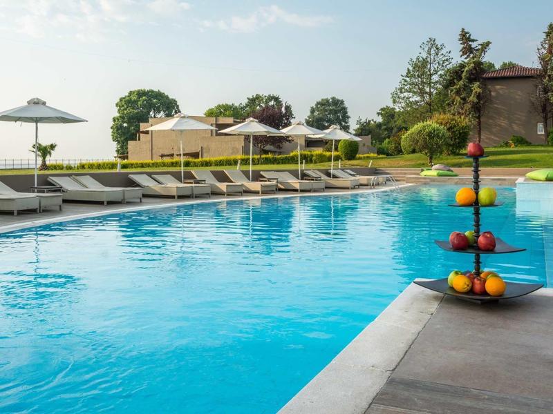 Outdoor pool area with loungers, umbrellas, and fruit stand under clear sky.