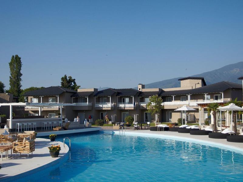 Outdoor hotel pool with sun loungers and umbrellas under clear sky.