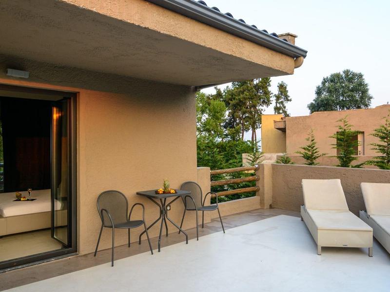 Outdoor patio with metal chairs and two lounge chairs outside a beige house.