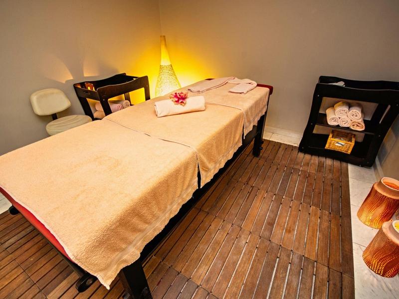 Cozy spa room with massage table, candles, towels, and soft lighting on wooden floor.
