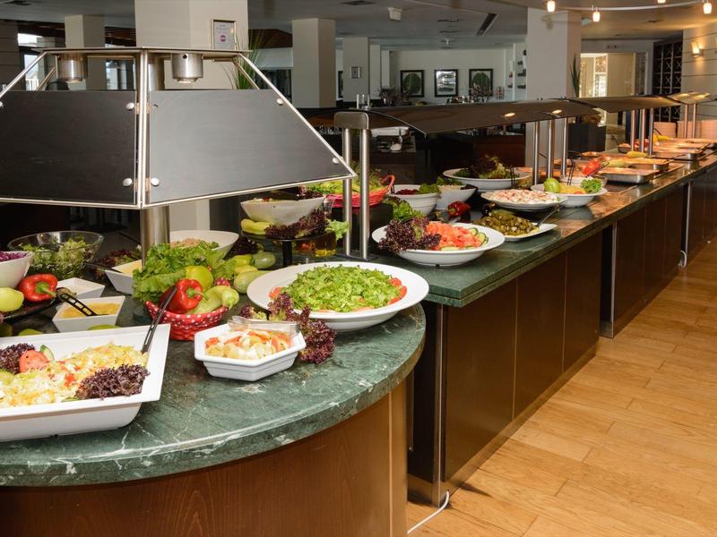 A buffet with various fresh salads and dishes on a marble counter in a restaurant.