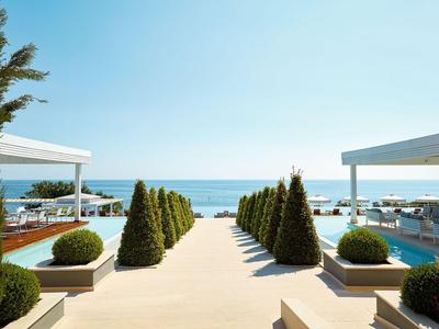 Helles Hotelzimmer mit Meerblick, Doppelbett, Schreibtisch und Balkon.