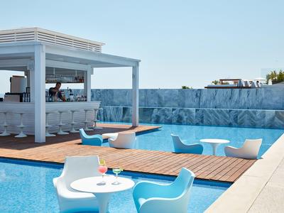 Moderner Poolbereich mit blauem Wasser, weißen und blauen Stühlen und einer Bar im Hintergrund.