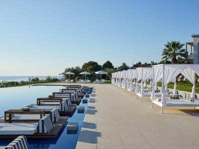 Luxuriöser Poolbereich mit Liegen und weißen Vorhängen neben dem Meerblick.