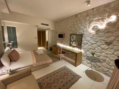 Helles, modernes Schlafzimmer mit Steinwand, Doppelbett, Teppich und Schreibtisch mit Spiegel.