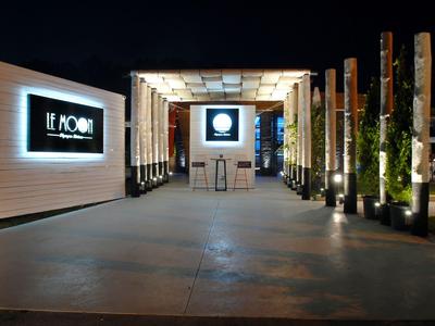 Moderner Hotel-Eingang bei Nacht mit beleuchtetem Schild und dekorativen Holzsäulen.