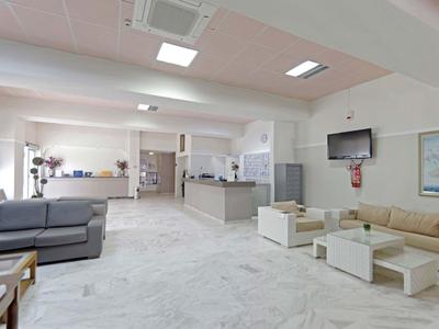 Helle Hotellobby mit moderner Möblierung, Sofas und einem Flachbildfernseher an der Wand.