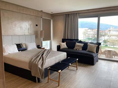 Modernes Schlafzimmer mit großem Bett, Sofa, Fensterfront und Blick auf eine Berglandschaft.