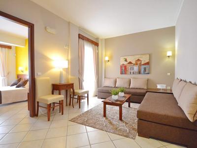 Helles Wohnzimmer mit braunen Sofas, Teppich, kleinem Tisch und Zugang zu einem Schlafzimmer.