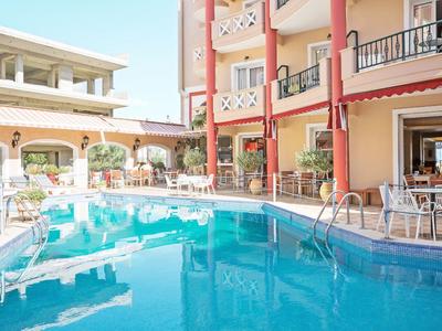 Hotelbereich mit klar blauem Schwimmbecken, roten Säulen und Café mit Tischen und Stühlen.