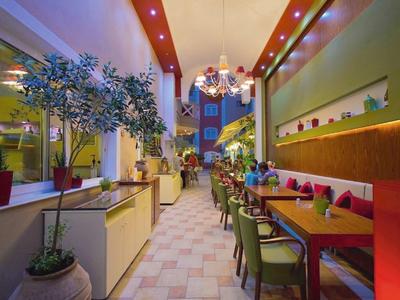 Cozy restaurant with modern lighting, green plants, and set tables in a warm atmosphere.