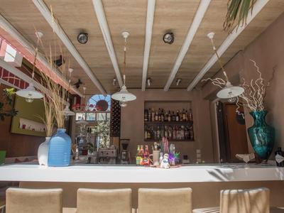 Barbereich mit weißen Stühlen, Tresen, Dekorationsvasen und Regalen mit Flaschen in einem Hotel.