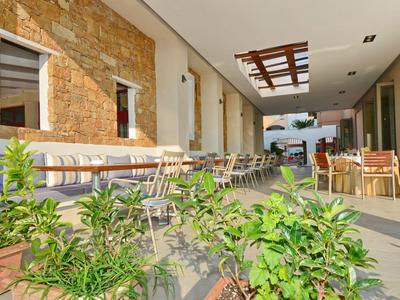 Moderner Außenbereich eines Restaurants mit Tischen, Stühlen und Pflanzen.