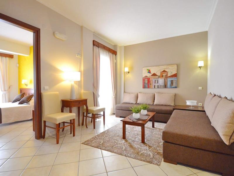 Helles Wohnzimmer mit braunen Sofas, Teppich, kleinem Tisch und Zugang zu einem Schlafzimmer.