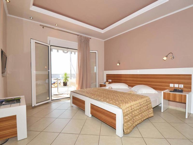 Helles Hotelzimmer mit Doppelbett, Flachbildschirm, Balkon und hellen Fliesenboden.