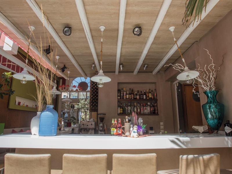 Moderne Bar mit hellen Hockern, verschiedenen Flaschen und dekorativen Vasen auf der Theke.