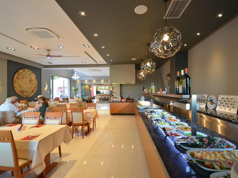 Helles Restaurant mit modernen Lampen, Buffettheke rechts und Gästen an Tischen links.