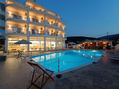 Beleuchtetes Hotel mit Pool und sitzenden Stühlen bei Abenddämmerung