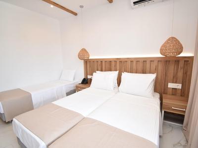 Helles Schlafzimmer mit zwei Einzelbetten, weißen Wänden, Holzkopfteil und beige Bettwäsche.