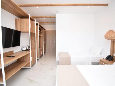 Hell eingerichtetes Schlafzimmer mit weißen Wänden, Holzregalen, Bett und Flachbildfernseher.