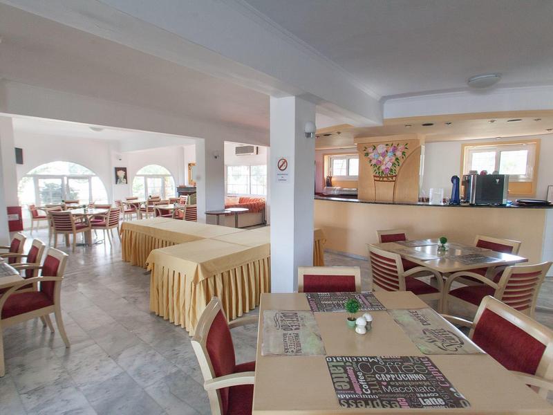 Großer heller Speisesaal mit Tischdecken, roten Stühlen und Theke im Hintergrund.