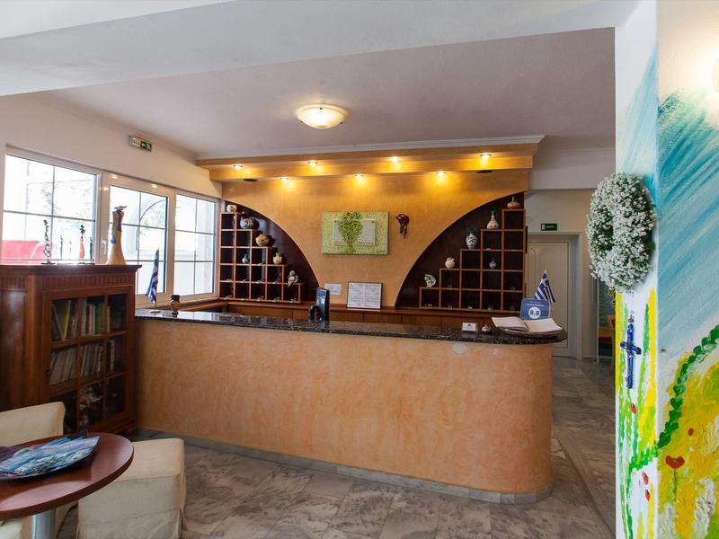 Moderne Rezeption mit hellbraunem Tresen, Holzmöbeln und Kunst an weißer Wand.