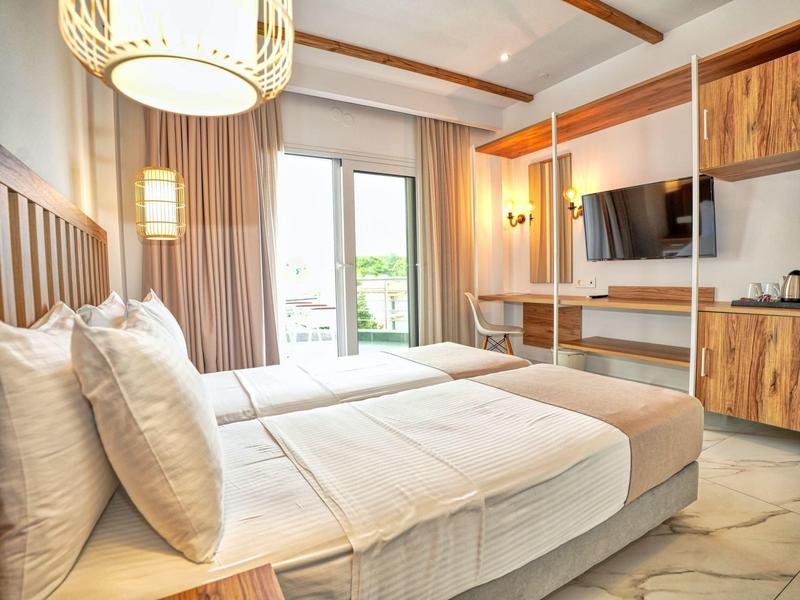 Gemütliches Hotelzimmer mit Doppelbett, großem Fenster, Holzmöbeln und modernem TV.