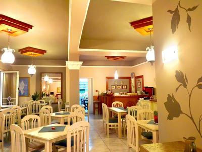 Helles Restaurant mit weißen Holzmöbeln und warmen Wandfarben.