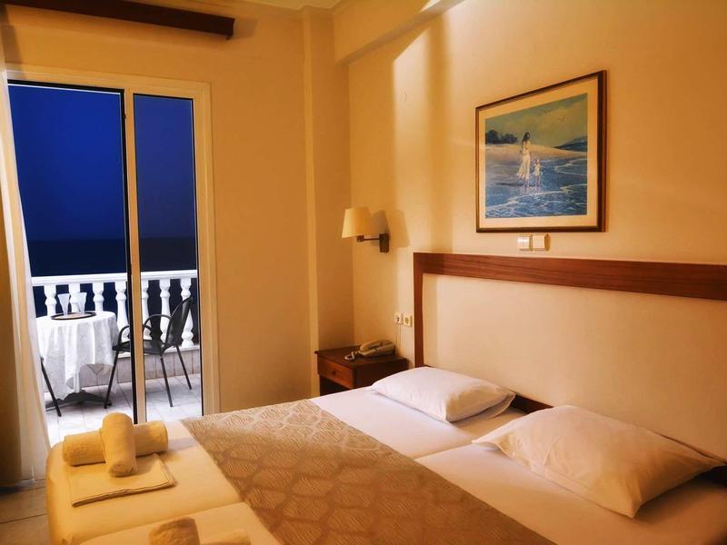 Gemütliches Schlafzimmer mit Doppelbett, Balkon und Blick auf das Meer bei Abenddämmerung.