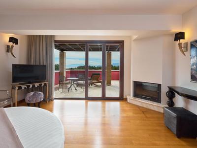 Habitación de hotel luminosa con suelo de madera, terraza y vista al mar.