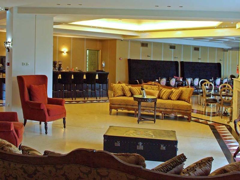 Großer heller Wohnraum mit roten Sesseln, gelbem Sofa und großen Fenstern, viel Tageslicht.