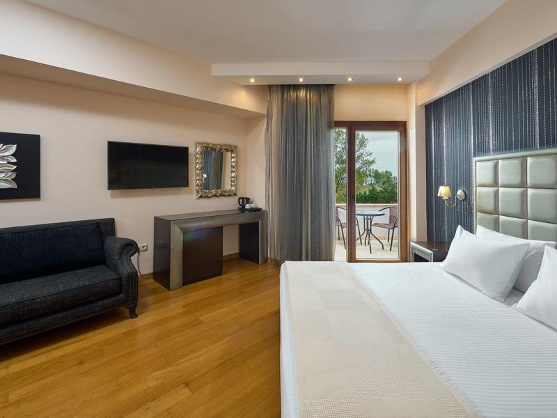 Modernes Hotelzimmer mit großem Bett, Sofa, Schreibtisch, Flachbildschirm und Balkon mit Aussicht.