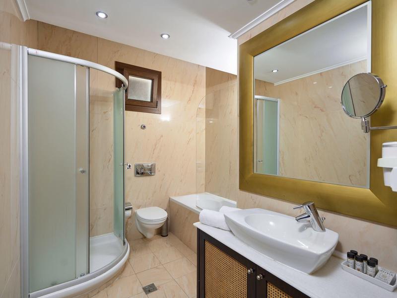 Modernes Badezimmer mit Runddusche, Toilette, Badewanne, großem Spiegel und Waschbecken auf Holzschrank.