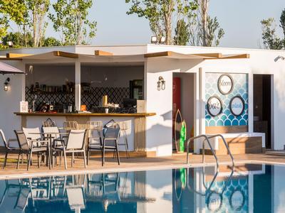 Moderner Außenpool mit Bar und Sitzgelegenheiten in einem Hotel.