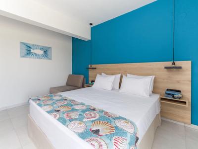 Modernes Hotelzimmer mit Doppelbett, blauer Akzentwand, Nachttisch und minimaler Dekoration.