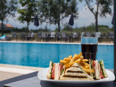 Sandwiches mit Pommes und einem Glas Cola neben einem Pool im Freien.