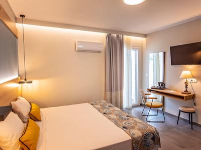 Gemütliches Schlafzimmer mit großem Bett, Schreibtisch, Stuhl, TV und warmem Licht.