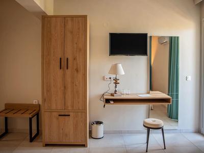 Gemütlicher Raum mit Holzmöbeln, Fernseher, kleinem Tisch und Stuhl vor hellem Wandspiegel.