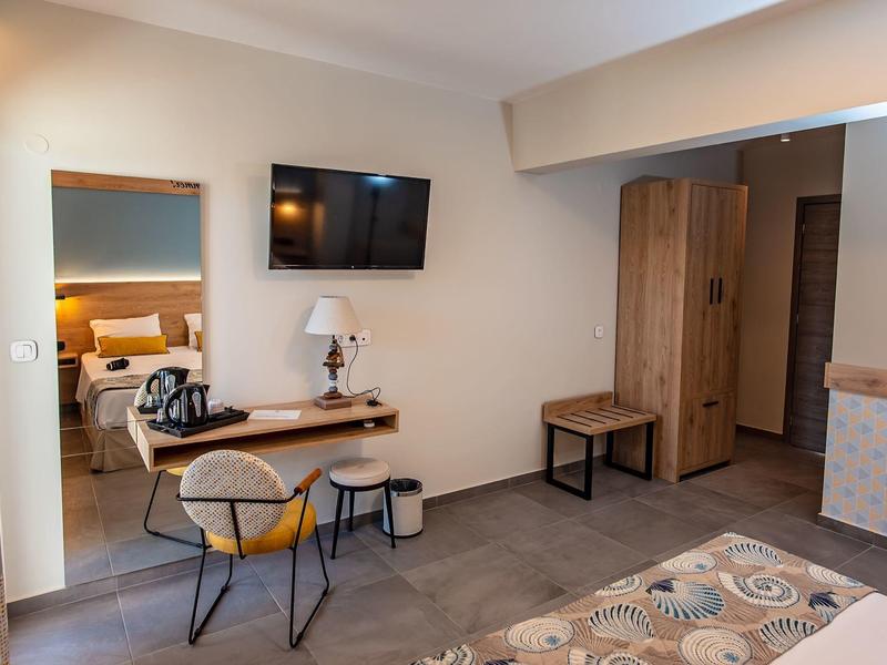 Moderner Hotelzimmerbereich mit Schreibtisch, Stuhl, Fernseher und Kleiderschrank in neutralen Tönen.