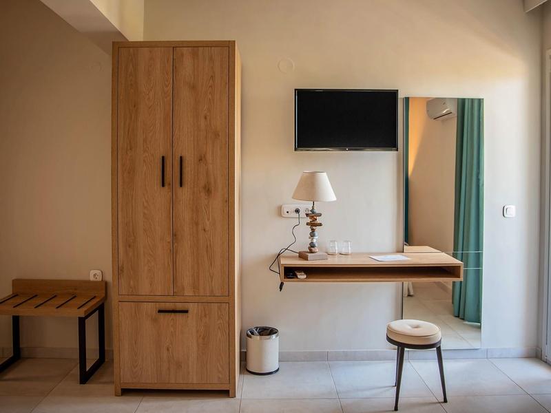 Gemütlicher Raum mit Holzmöbeln, Fernseher, kleinem Tisch und Stuhl vor hellem Wandspiegel.