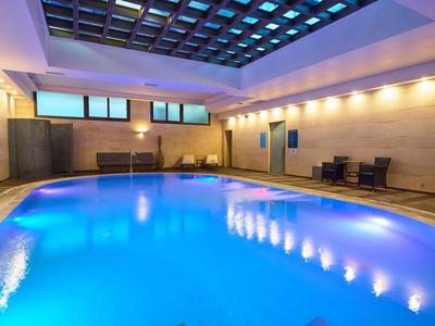 Hotelowy basen kryty z niebieską wodą i nowoczesną atmosferą.