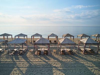 Plaża z rzędami parasoli i leżaków o poranku nad morzem.