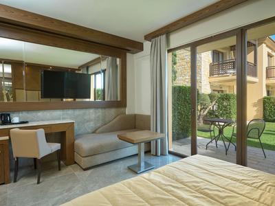 Pokój hotelowy z wygodnym miejscem do siedzenia i tarasem, meble ogrodowe z widokiem na sąsiednie budynki.