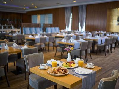Elegancka hotelowa jadalnia z nakrytymi stolikami i talerzem śniadaniowym na pierwszym planie.