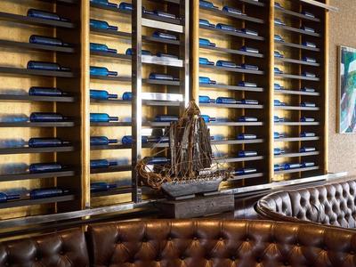 Elegancki hotelowy salon z ciemnymi skórzanymi siedzeniami i dekoracyjnym regałem na wino na ścianie.