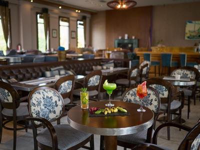 Elegancka restauracja hotelowa z stylowymi meblami i kolorowymi koktajlami na okrągłym stole.