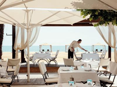 Terrasse mit gedeckten Tischen und Blick aufs Meer, Personal bereitet Tisch vor