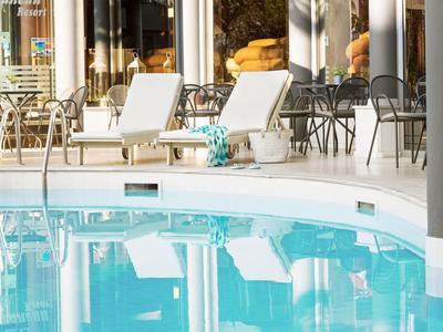 Moderner Hotelpool mit Liegestühlen und Sitzbereichen im Hintergrund.