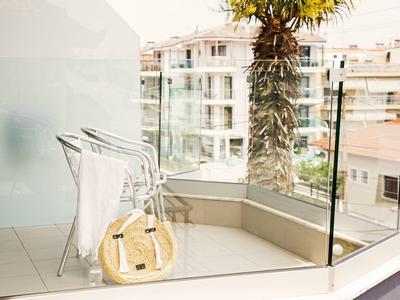 Balkon s bílými židlemi, slaměnou taškou a palmou ve městě.